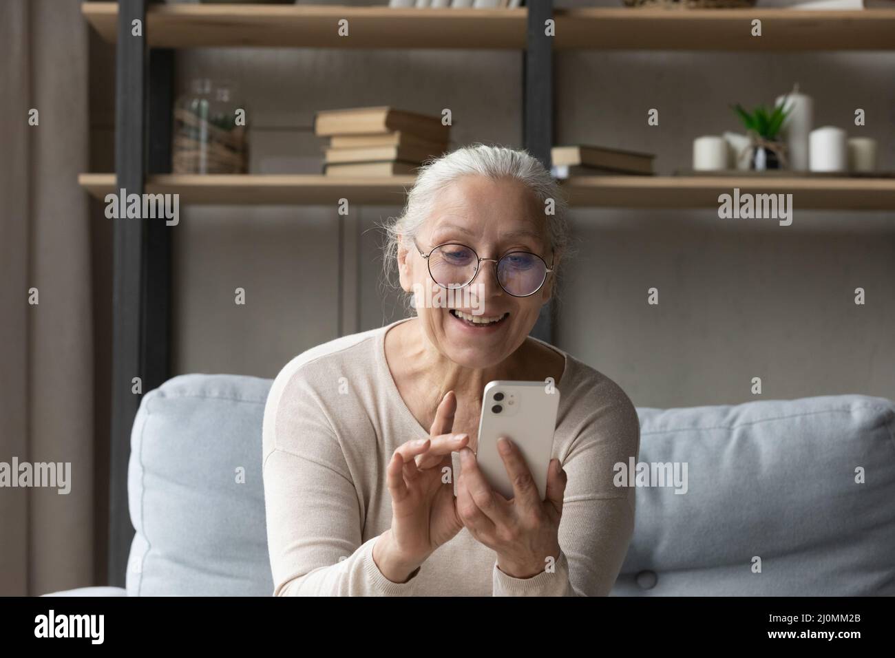 Donna sorridente grigio-capelli donna leggere messaggio utilizzare smartphone Foto Stock