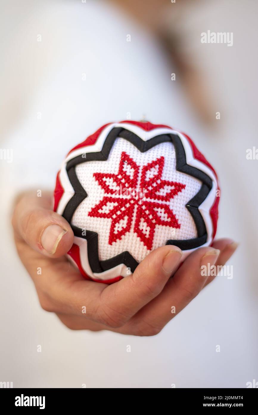 Donna che tiene Patch lavoro Natale palla ornamento in mano . Maglia a croce in fiocco di neve. Decorazioni natalizie. Foto Stock