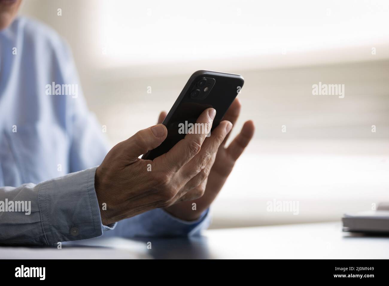 Chiudi le mani più vecchie di una donna che tiene in mano lo smartphone Foto Stock