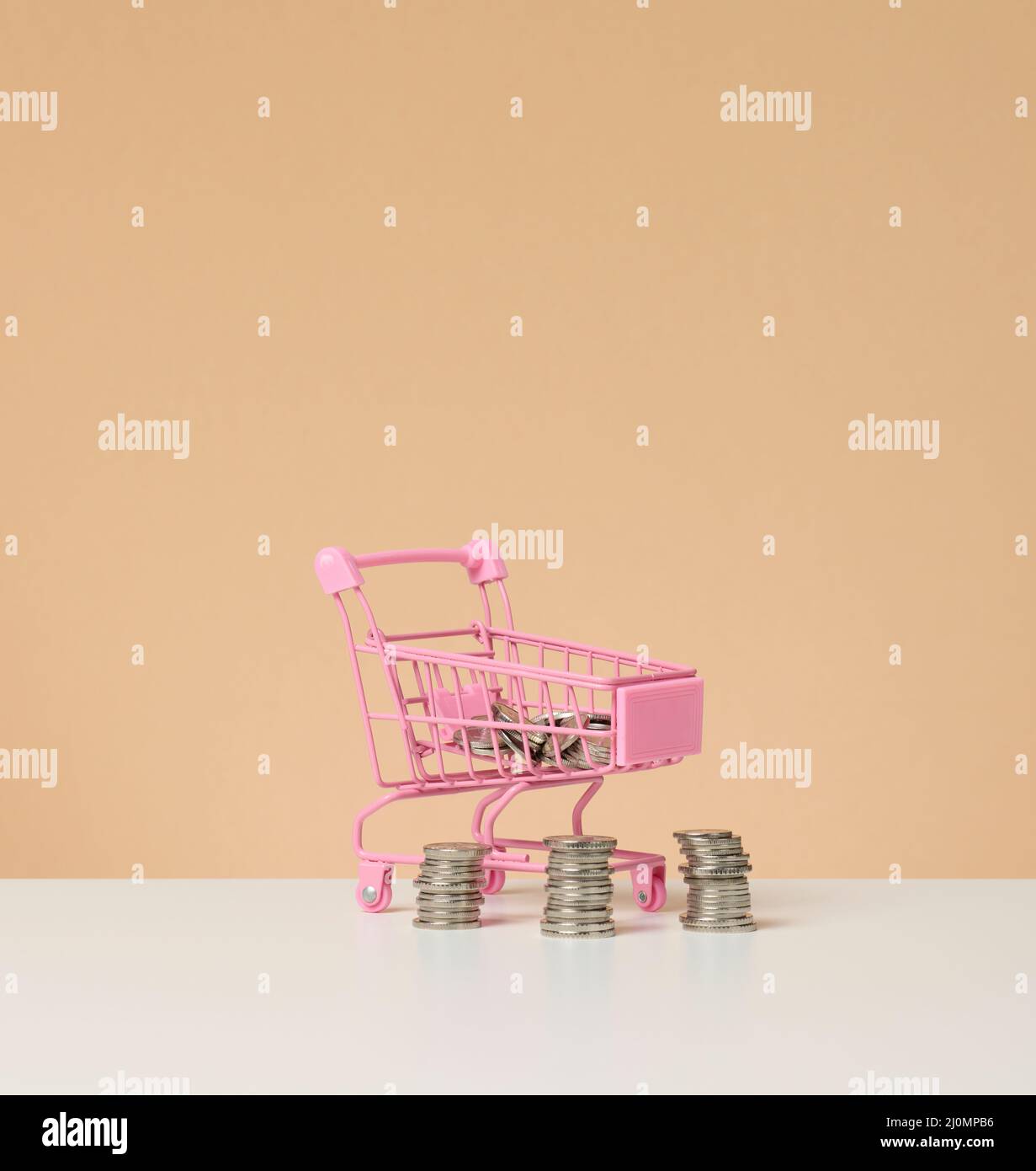 Carrello in metallo e piccolo cambio su un tavolo bianco. Concetto di risparmio, sconti Foto Stock