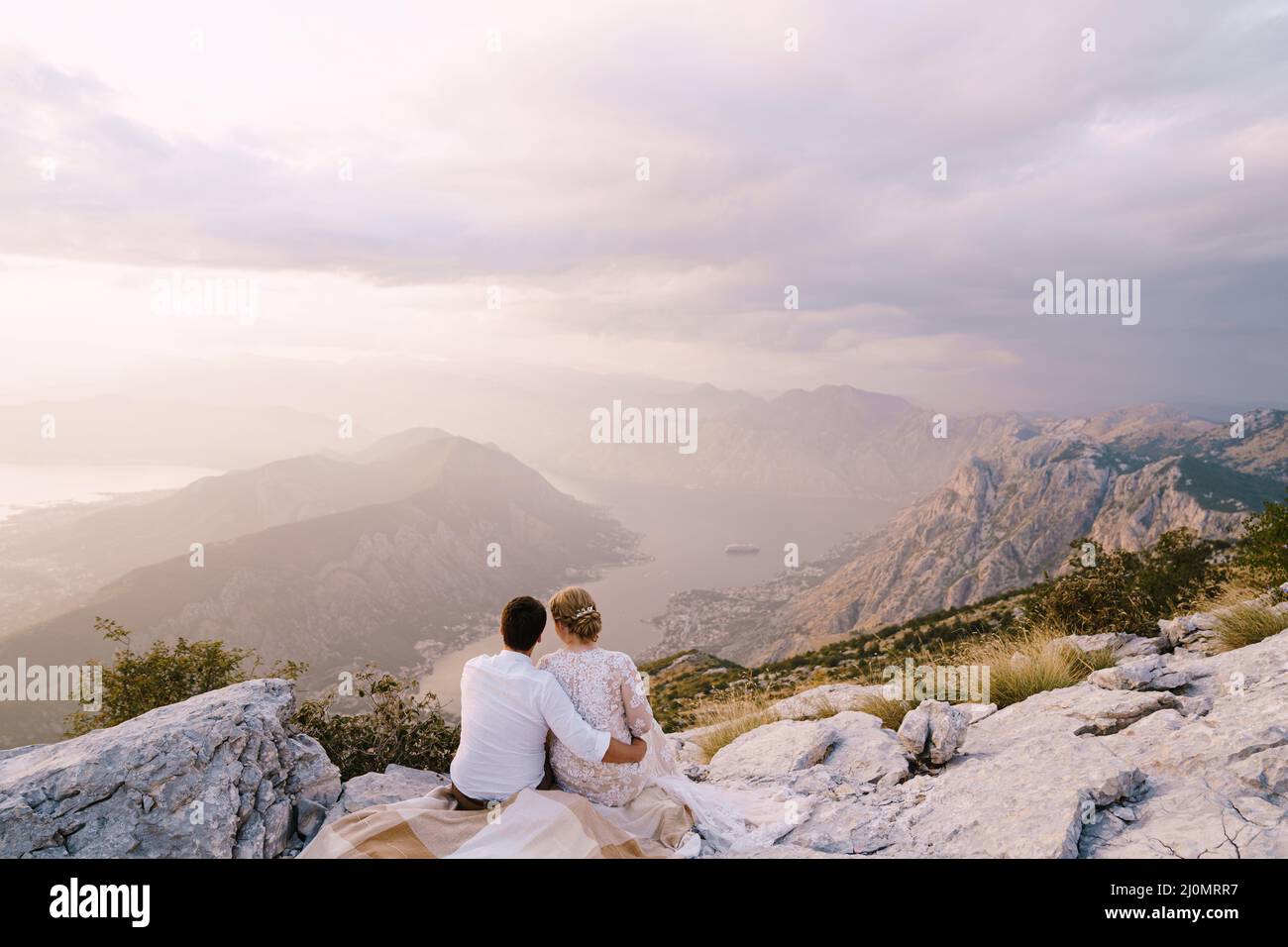 Sposa e sposo siediti sulla montagna e guarda la baia Foto Stock