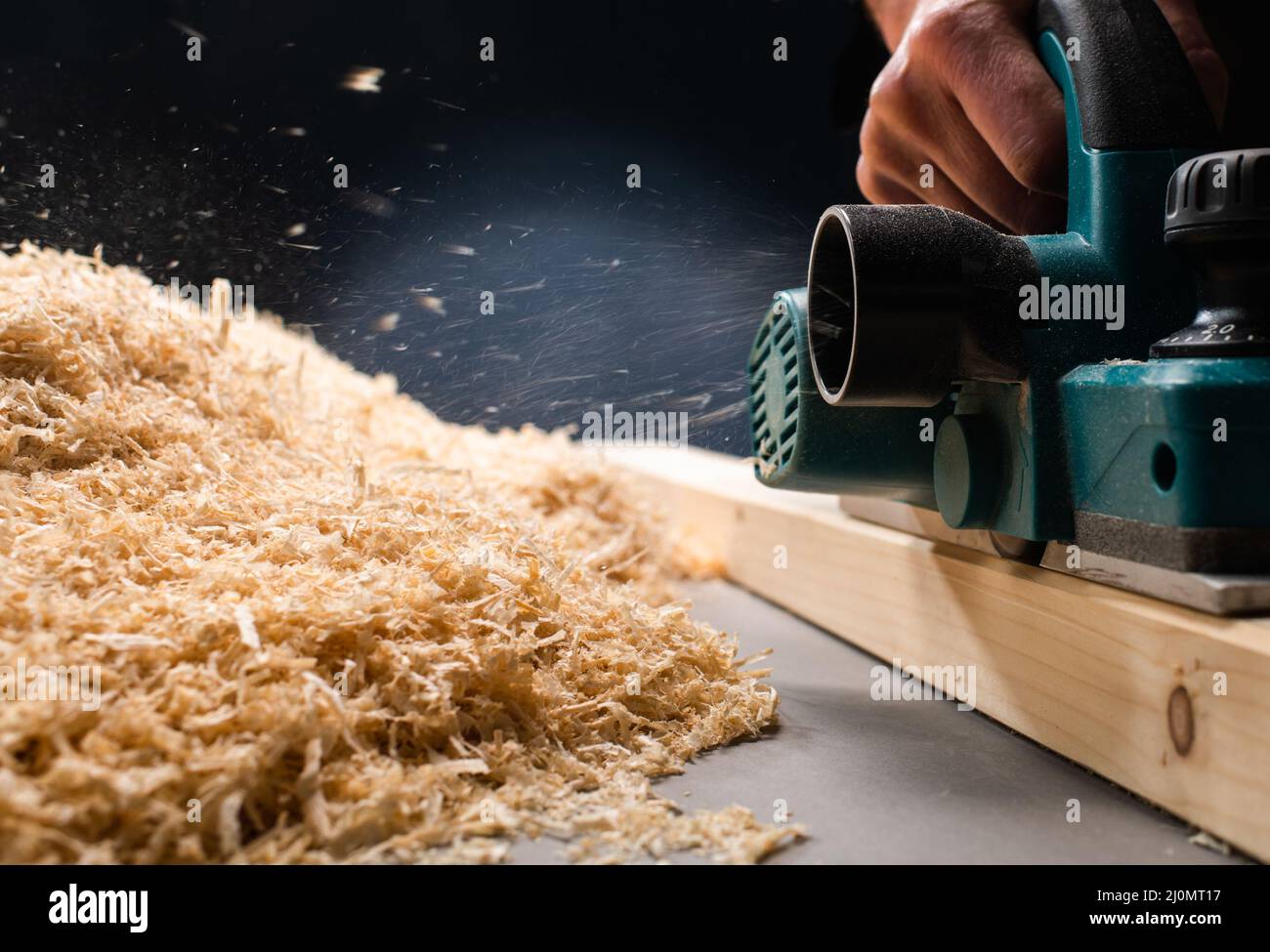 Lavoratore piallare il piano di un tavolo di legno con un piano elettrico. Foto Stock