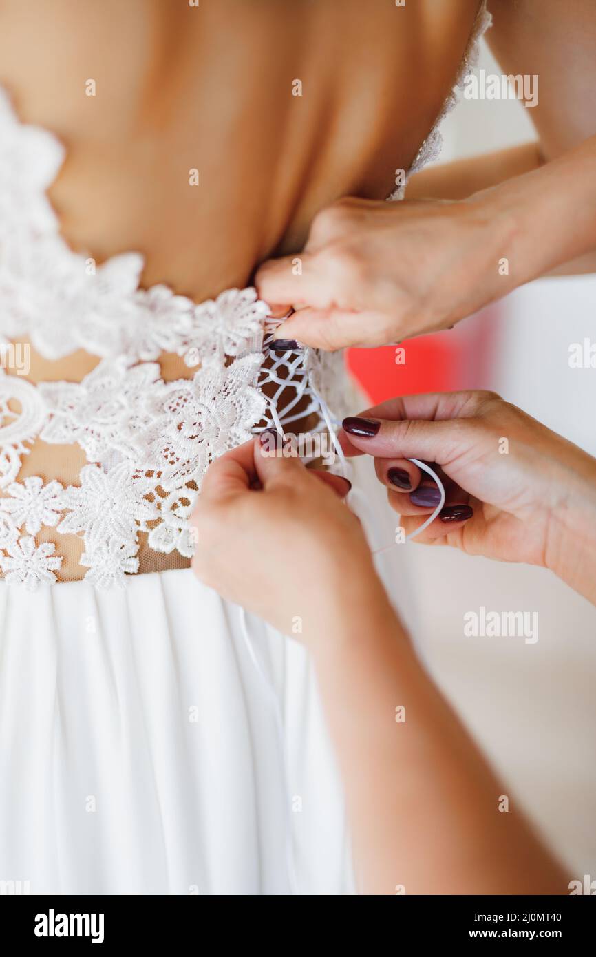 Le mani delle donne stringono il corsetto in pizzo dell'abito da sposa. Primo piano Foto Stock