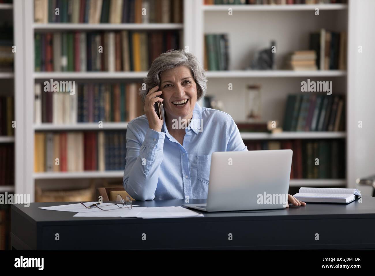 Una donna d'affari di mezza età parla con lo smartphone durante la giornata lavorativa Foto Stock