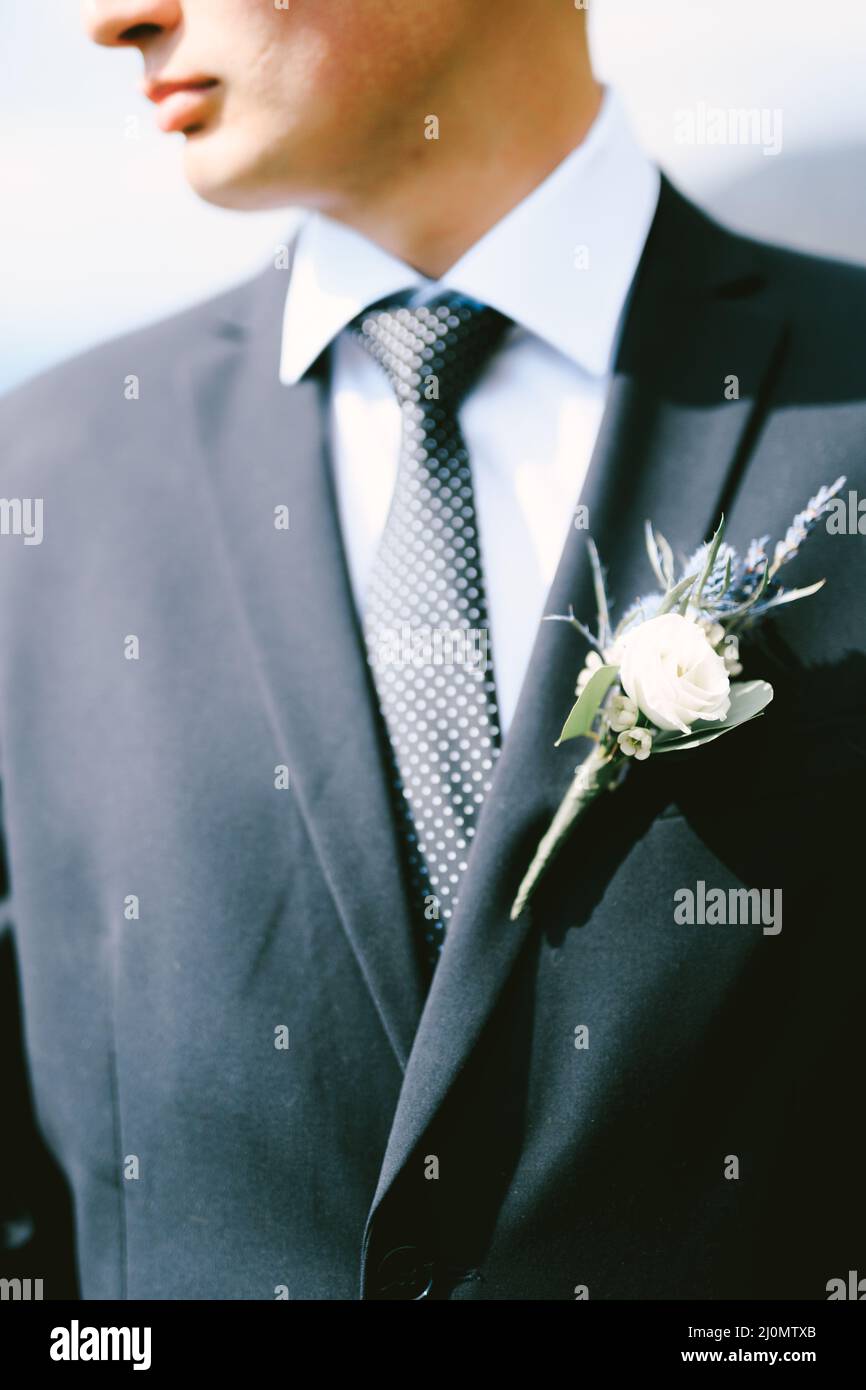 Indossate una giacca nera, una camicia bianca, una cravatta a pois con boutonniere. Primo piano Foto Stock