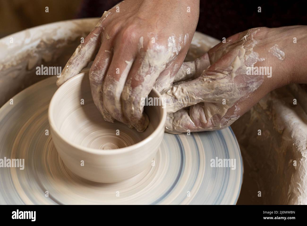 Le mani sporche modellano la rotella del vasaio di creta Foto Stock