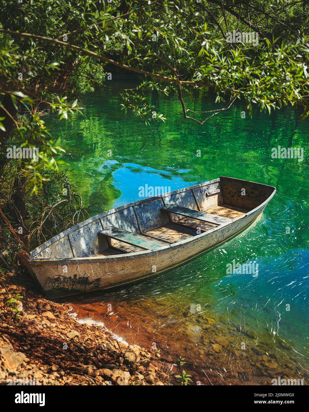 Vecchia barca di pescatori sulla riva del fiume smeraldo Foto Stock
