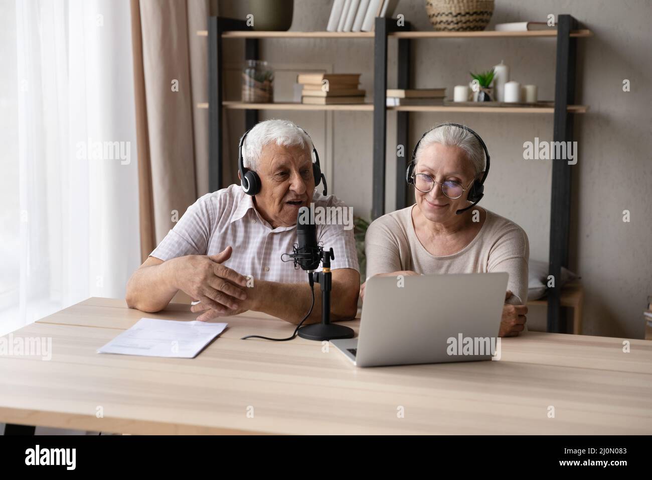 I coniugi anziani utilizzano un computer portatile per parlare nel microfono Foto Stock