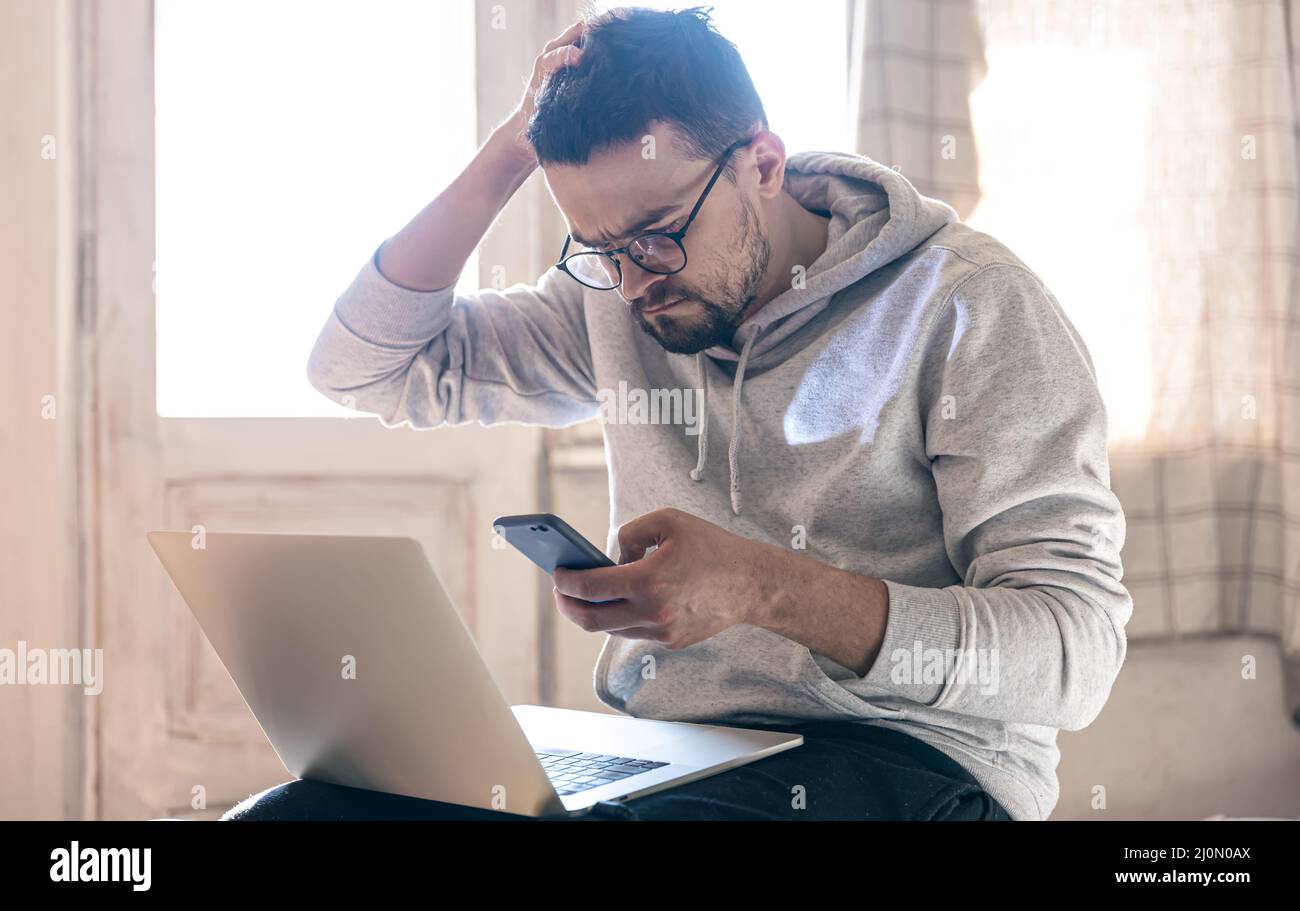 Un uomo con occhiali sta lavorando su un laptop. Foto Stock
