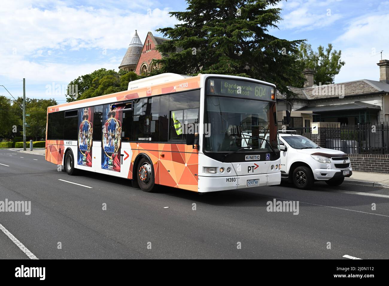 Route 604 bus, con logo del nuovo operatore Kinetic Melbourne, in livrea PTV bianca e arancione che corre lungo Orrong Rd nel pomeriggio Foto Stock