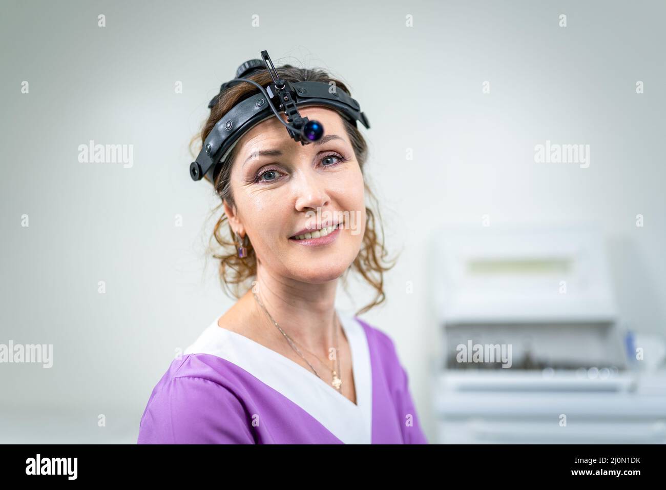 Ritratto di fidato medico femminile. Medico ENT femminile in abiti medici viola che posano in ufficio della clinica sulla sua testa con Foto Stock