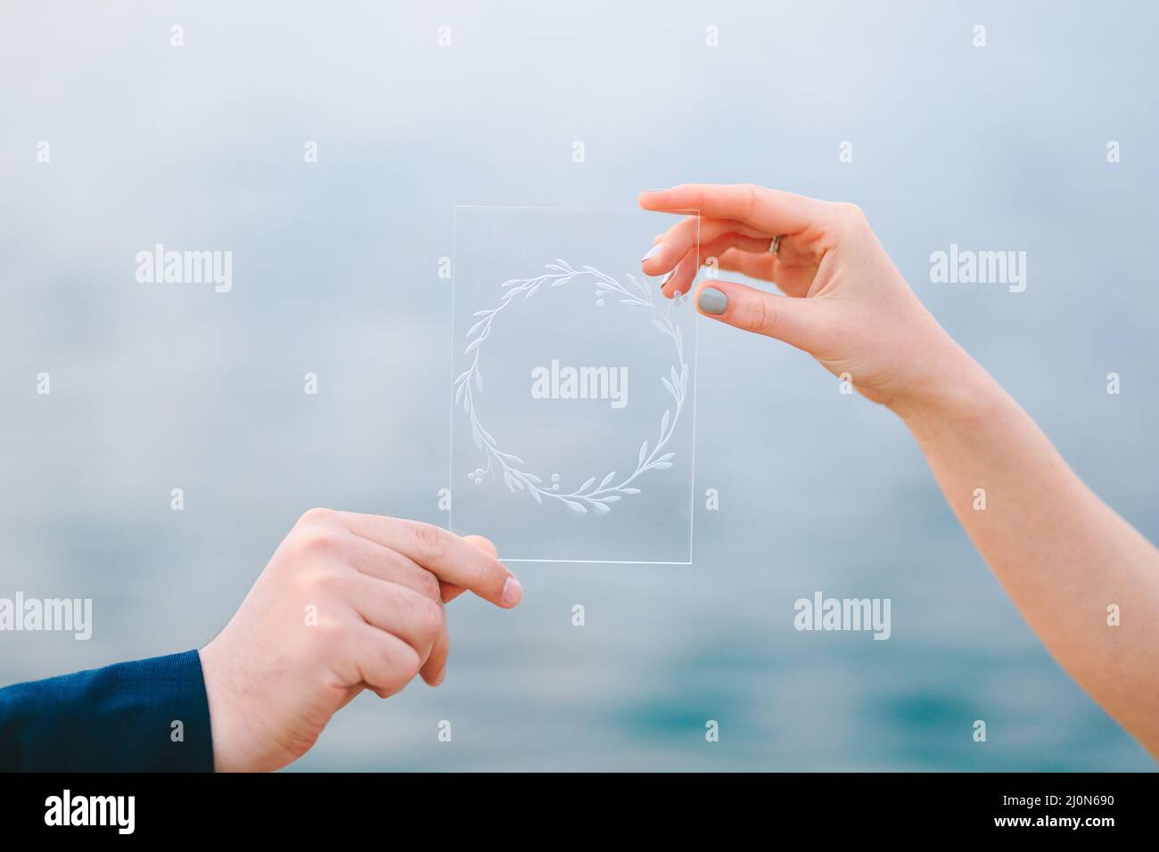 Mano maschio e femmina che tiene un quadro trasparente che raffigura una corona Foto Stock