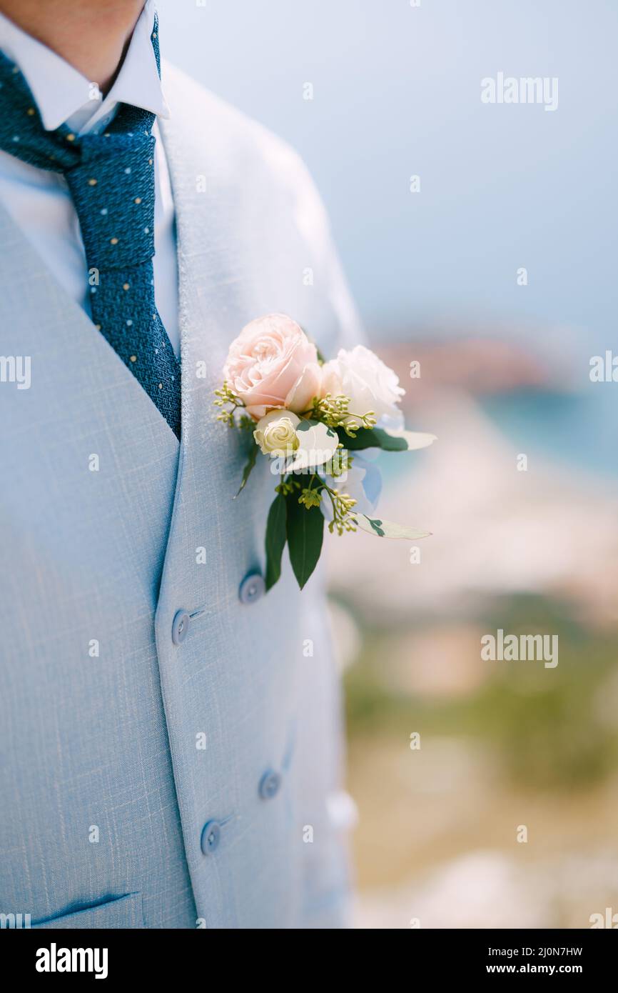 Un uomo in gilet blu, cravatta blu e un delicato boutonniere con rose e eucalipto, da vicino Foto Stock