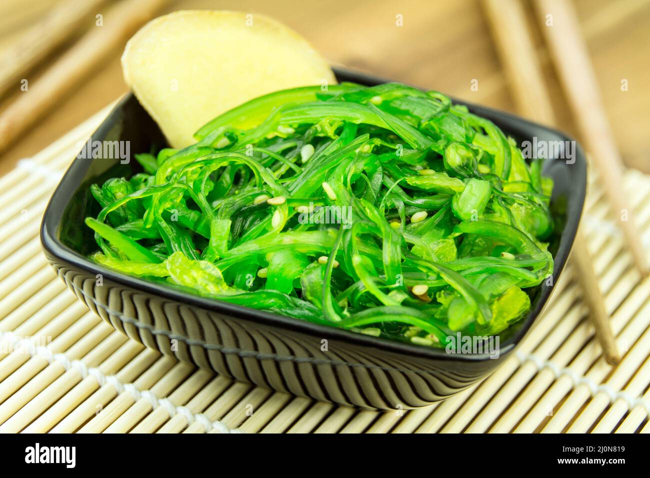 Insalata di alghe giapponesi wakame con zenzero su piano di bambù Foto Stock