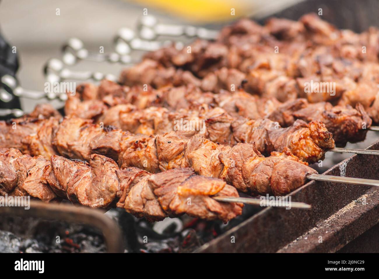Spiedino di carne di maiale, grigliato o arrostito in un barbecue a fuoco aperto e fiamme, shashlik o shashlik per un pic-nic con pitchforks, primo piano Foto Stock