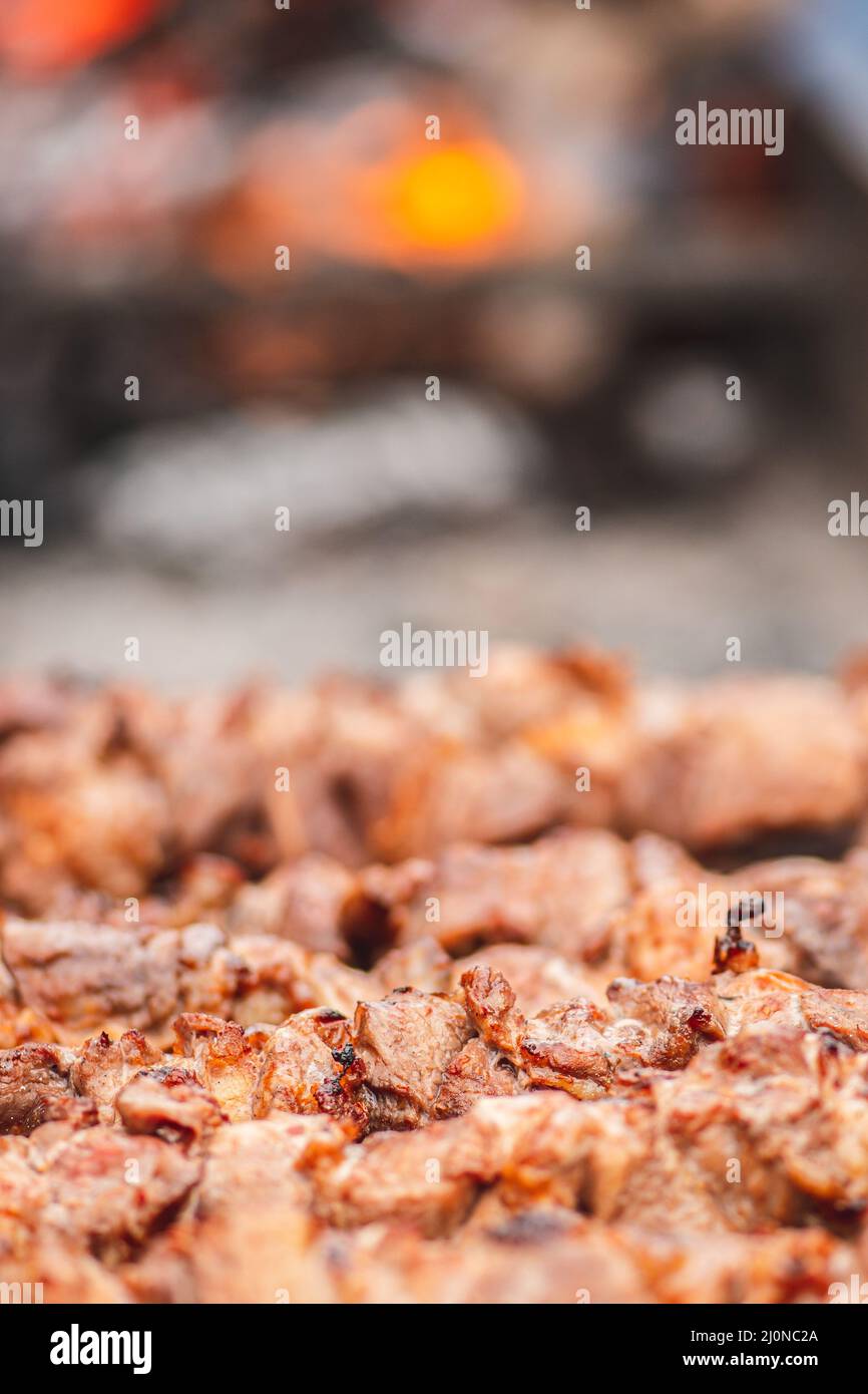 Spiedino di carne di maiale, grigliato o arrostito in un barbecue a fuoco aperto e fiamme, shashlik o shashlik per un pic-nic con pitchforks, primo piano Foto Stock