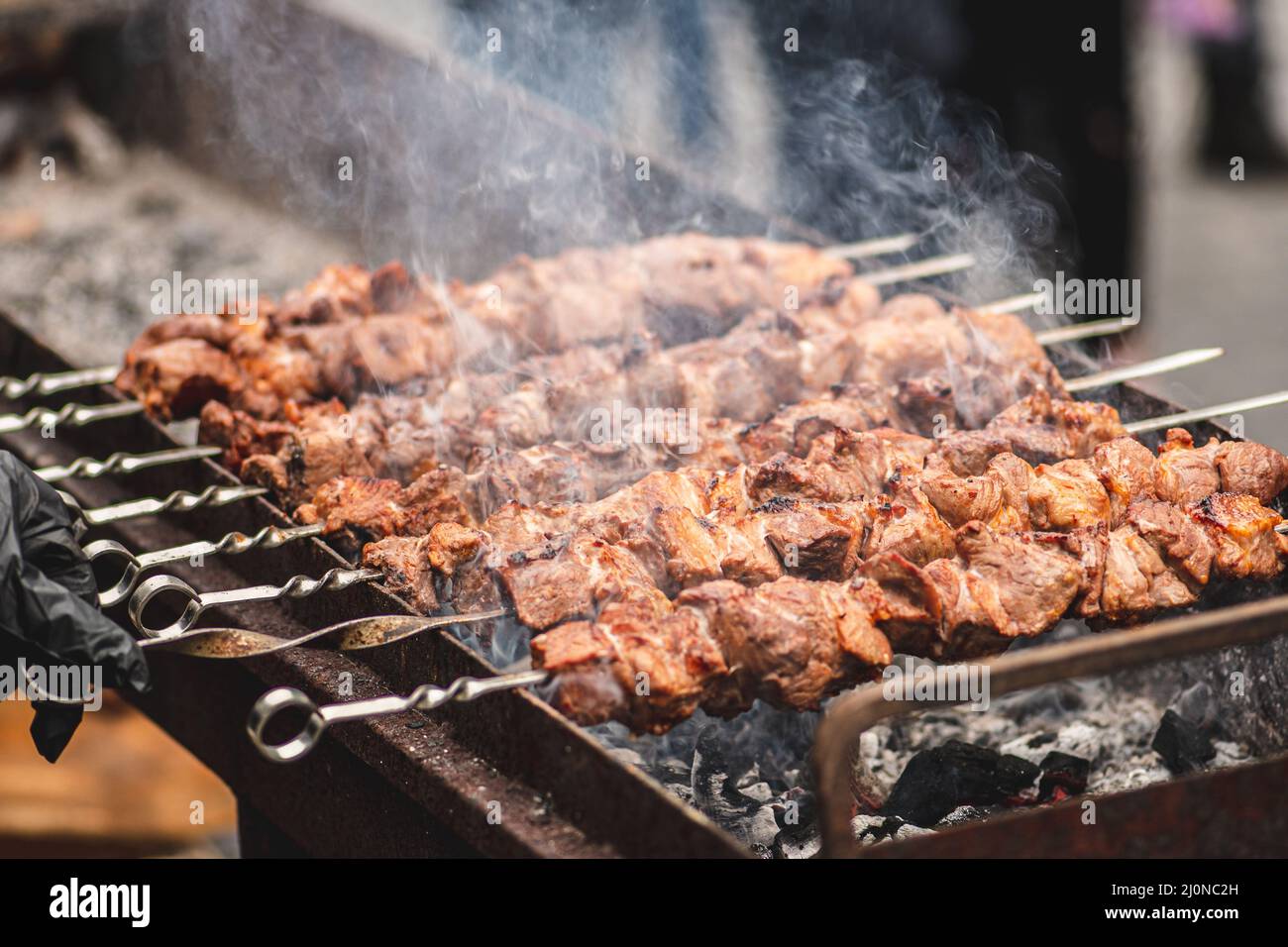 Spiedino di carne di maiale, grigliato o arrostito in un barbecue a fuoco aperto e fiamme, shashlik o shashlik per un pic-nic con pitchforks, primo piano Foto Stock