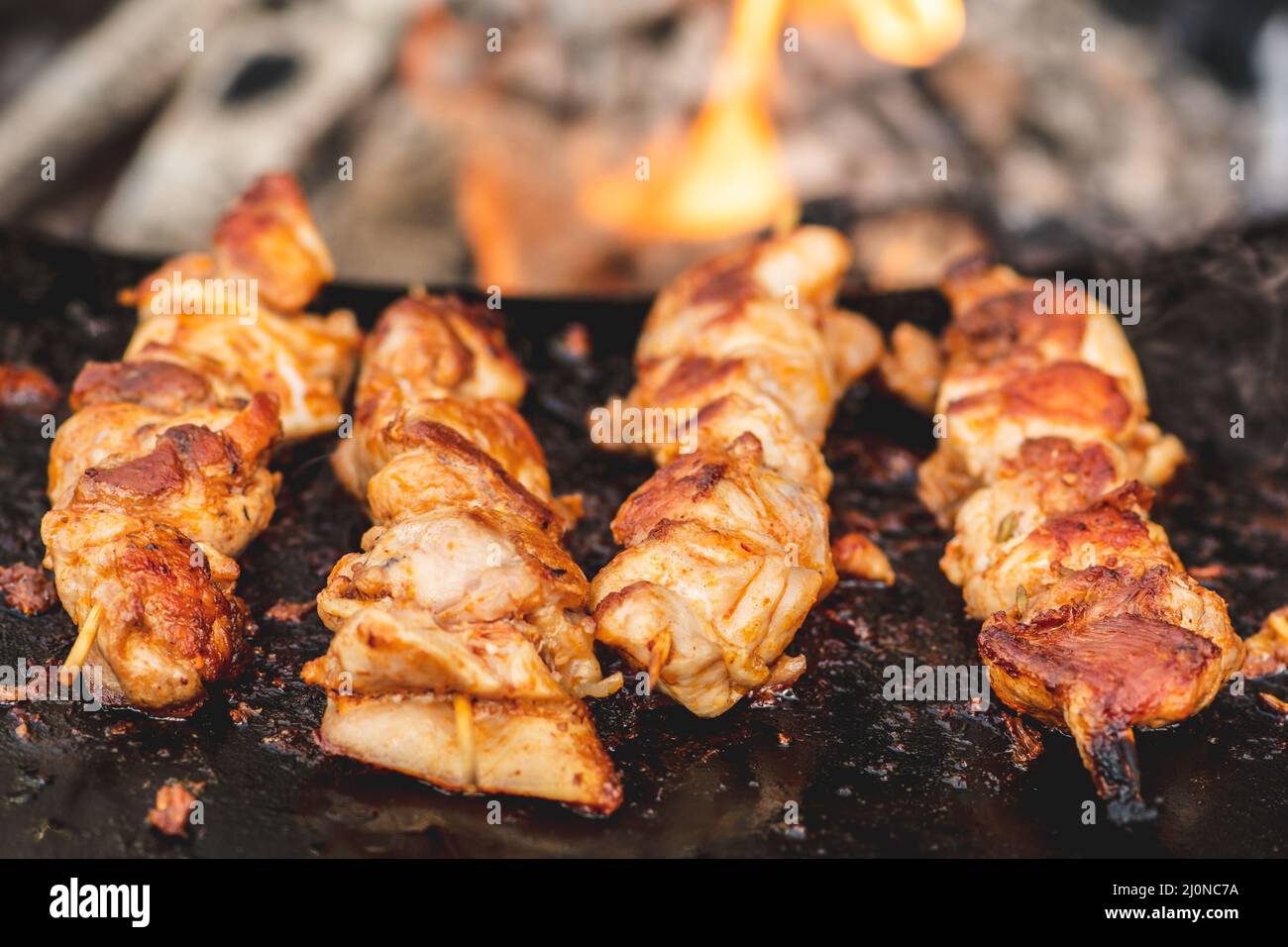 Preparare spiedini di carne di pollo, grigliati o arrostiti in un barbecue a fuoco aperto e fiamme, shashlik o shashlik per un pic-nic con pitchforks, chiudere Foto Stock