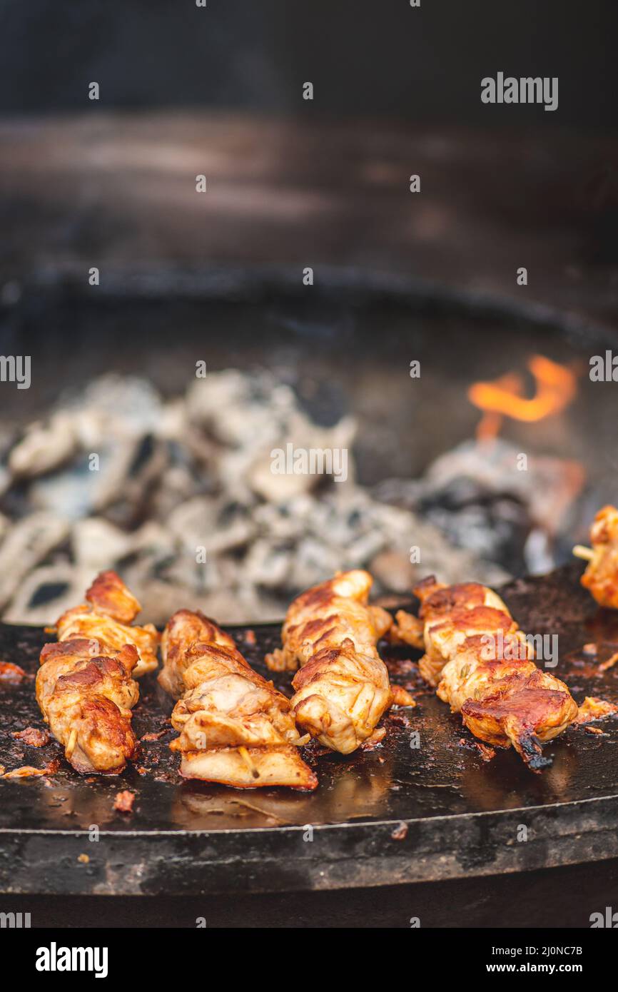 Preparare spiedini di carne di pollo, grigliati o arrostiti in un barbecue a fuoco aperto e fiamme, shashlik o shashlik per un pic-nic con pitchforks, chiudere Foto Stock