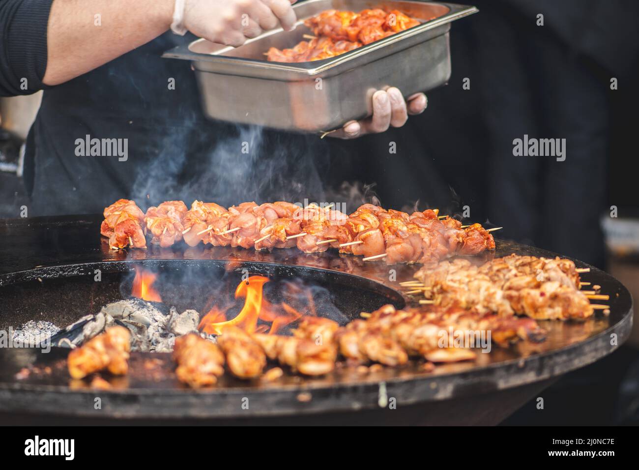 Preparare spiedini di carne di pollo, grigliati o arrostiti in un barbecue a fuoco aperto e fiamme, shashlik o shashlik per un pic-nic con pitchforks, chiudere Foto Stock