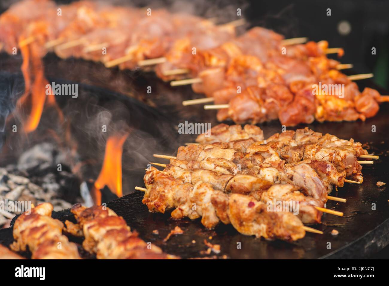 Preparare spiedini di carne di pollo, grigliati o arrostiti in un barbecue a fuoco aperto e fiamme, shashlik o shashlik per un pic-nic con pitchforks, chiudere Foto Stock