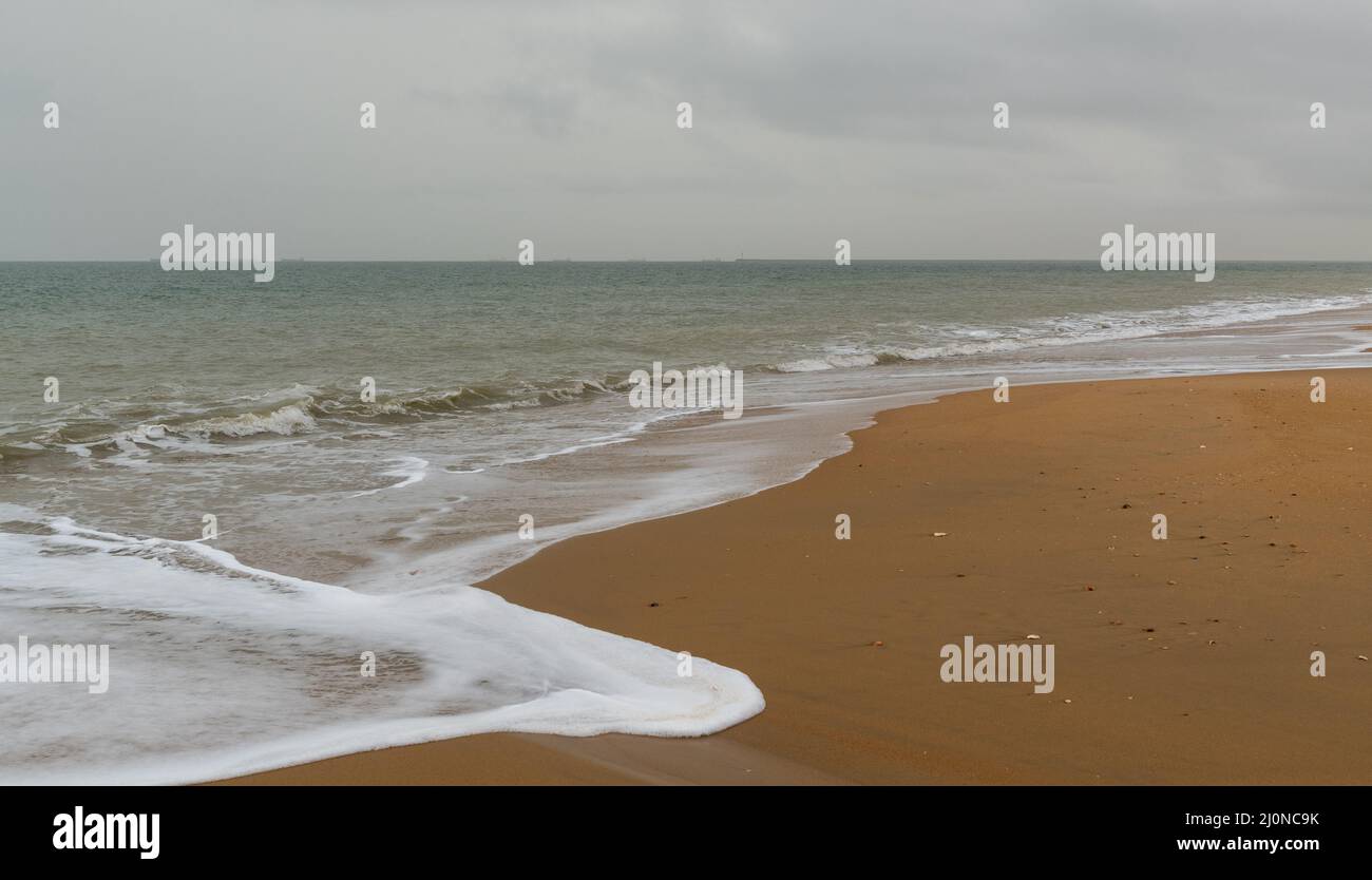 Una vista su una spiaggia bella e vuota con spiaggia e sabbia dorata Foto Stock