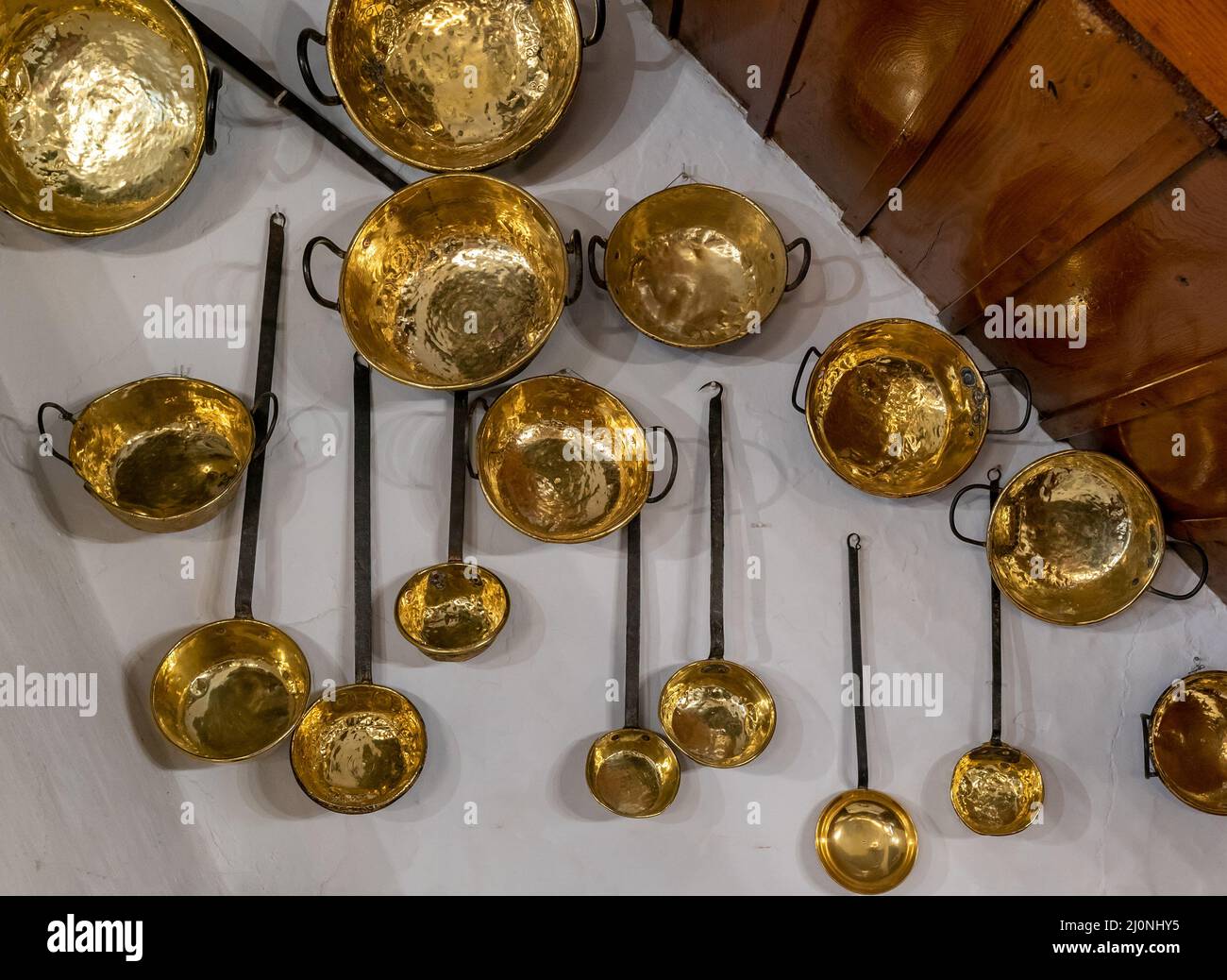 Aracena, Spagna - 16 Marzo, 2022: utensili da cucina in pewter e ottone montati sulle pareti di una tradizionale locanda e ristorante in Andalusia Foto Stock