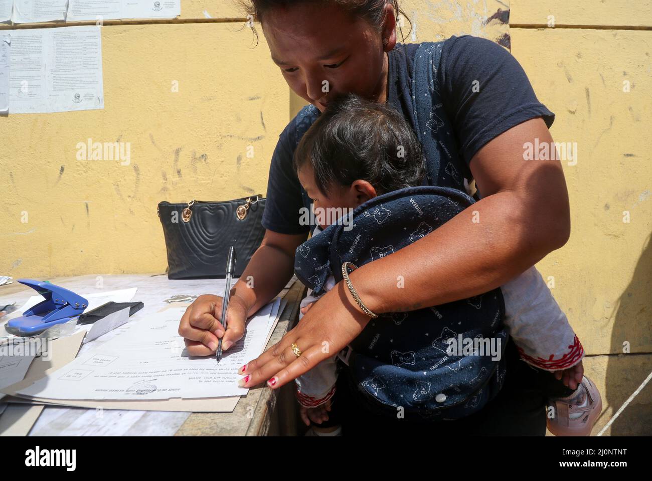 20 marzo 2022, Kathmandu, NE, Nepal: Sapana Tamang Gurung (21) riempie una forma di applicazione della polizia temporanea (polizia di Myadi) per le prossime elezioni locali a Kathmandu, Nepal il 20 marzo 2022. Â€œThough mio marito lavora in un negozio di mobili, il nostro status finanziario è ancora povero, così sono venuto qui per presentare domanda di polizia temporanea nella speranza di riempire alcune cose necessarie, â€ lei dice. (Credit Image: © Aryan Dhimal/ZUMA Press Wire) Foto Stock