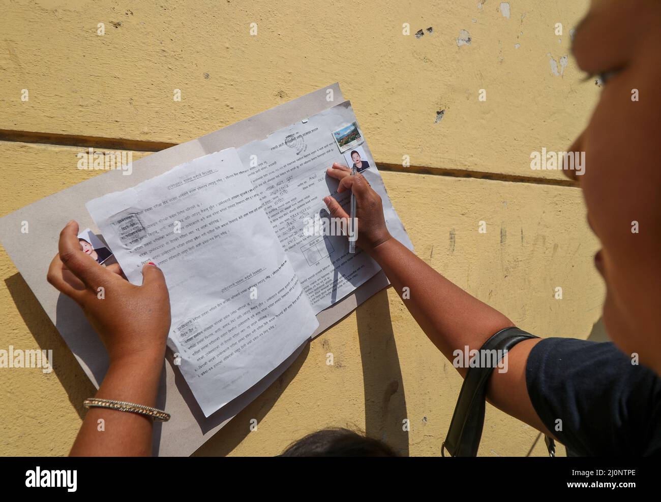 20 marzo 2022, Kathmandu, NE, Nepal: Sapana Tamang Gurung (21) riempie una forma di applicazione della polizia temporanea (polizia di Myadi) per le prossime elezioni locali a Kathmandu, Nepal il 20 marzo 2022. Â€œThough mio marito lavora in un negozio di mobili, il nostro status finanziario è ancora povero, così sono venuto qui per presentare domanda di polizia temporanea nella speranza di riempire alcune cose necessarie, â€ lei dice. (Credit Image: © Aryan Dhimal/ZUMA Press Wire) Foto Stock