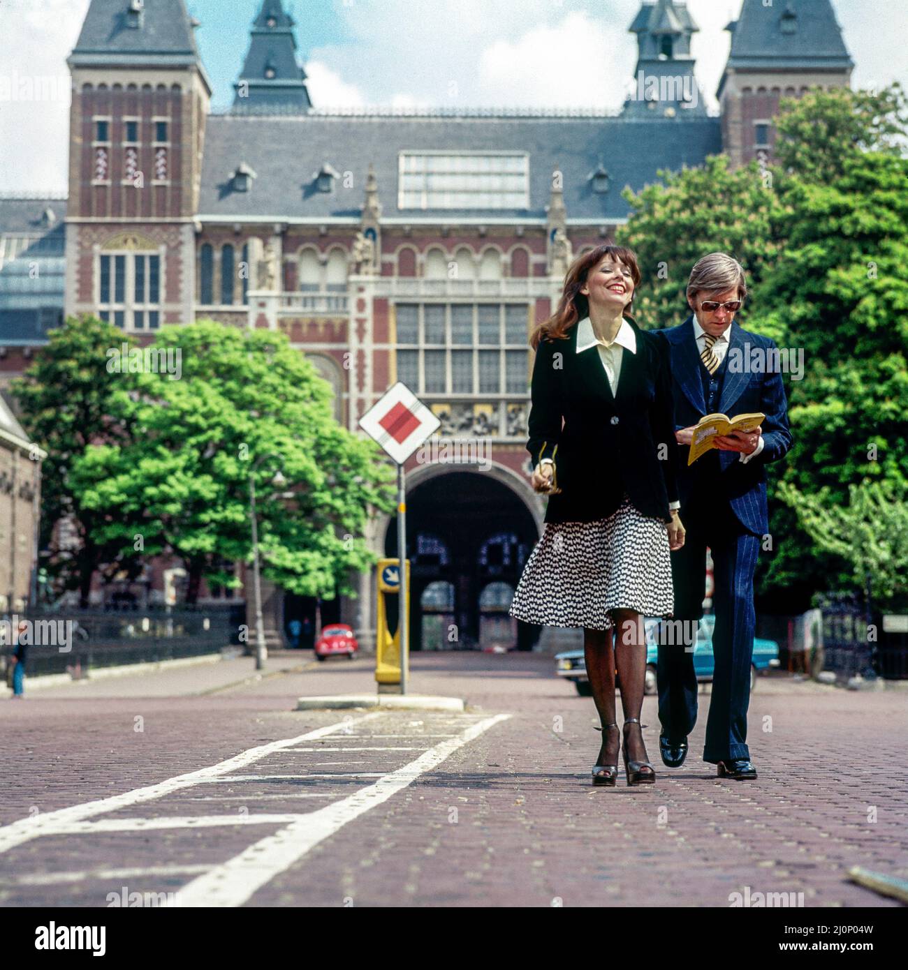 Vintage Amsterdam 1970s, elegante coppia di turisti di mezza età che passeggiando di fronte al Rijksmuseum, Olanda, Paesi Bassi, Europa, Foto Stock