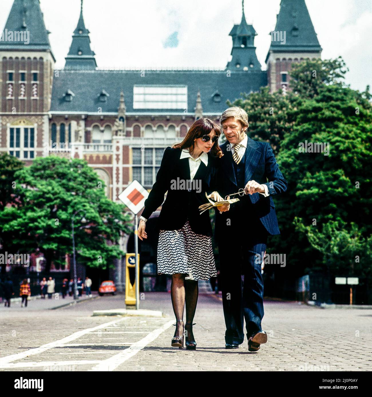 Vintage Amsterdam 1970s, elegante coppia di turisti di mezza età che passeggiando di fronte al Rijksmuseum, Olanda, Paesi Bassi, Europa, Foto Stock