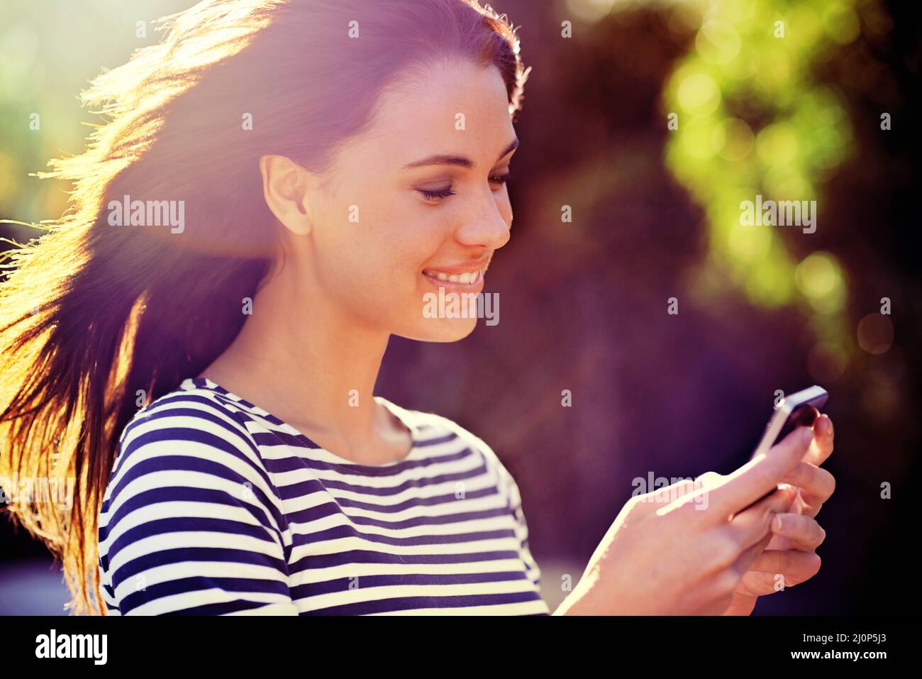 Buone connessioni. Scatto di una bella giovane donna utilizzando un telefono cellulare all'aperto. Foto Stock