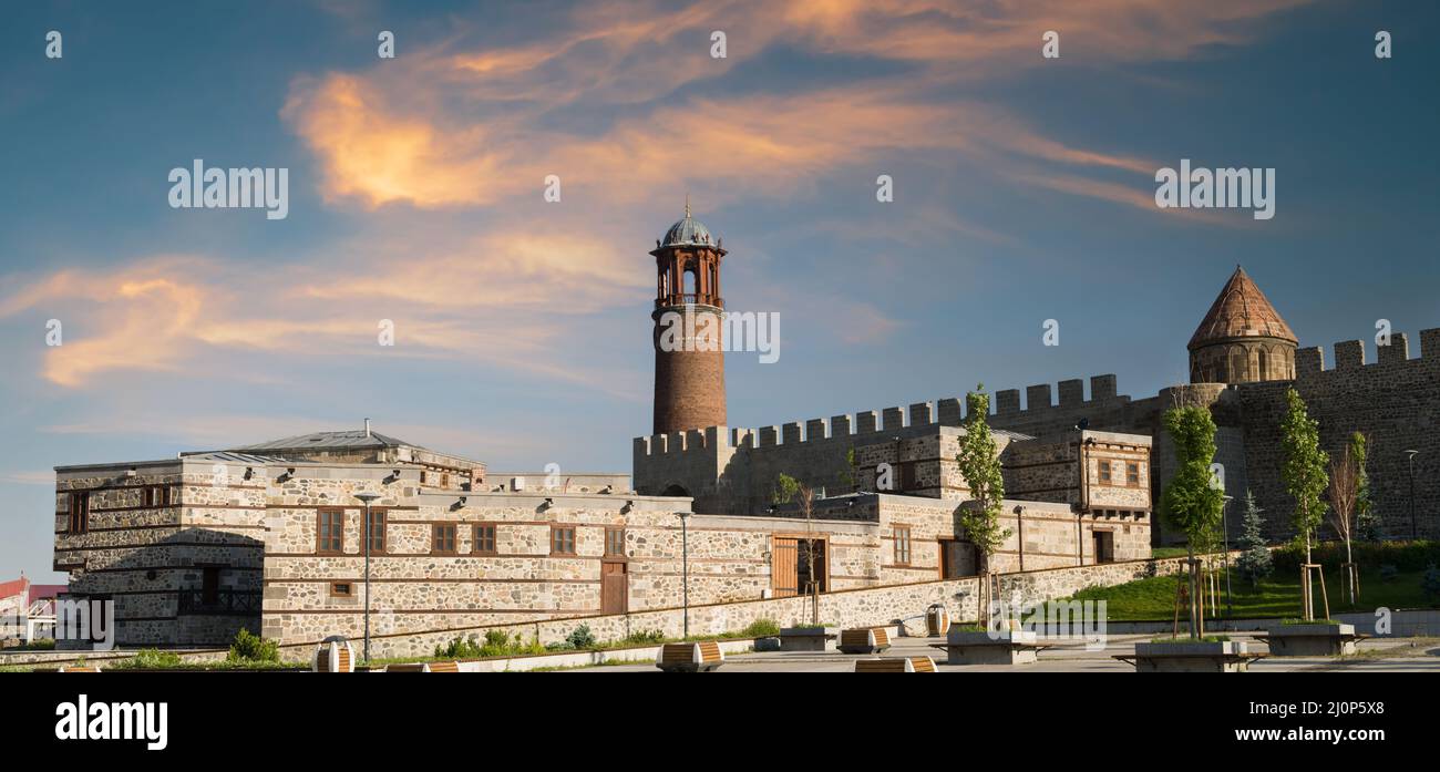 Erzurum Torre dell'Orologio e case in pietra tradizionale all'alba. Torre storica dell'Orologio sul Castello di Erzurum. Punti destinazioni di viaggio Turchia. Anat orientale Foto Stock