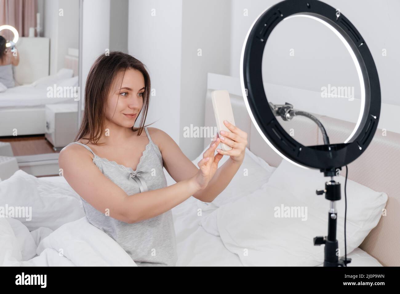 Video Vlog di registrazione femminile su smartphone a casa Online Influencer sul letto vicino. Streaming bellezza bloger Foto Stock