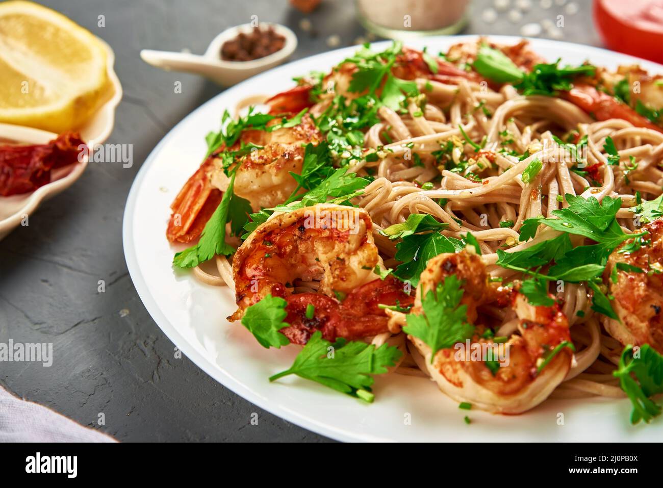 Friggere la noodle con gamberi e prezzemolo fresco sul piatto bianco, soba con gamberi, cucina asiatica Foto Stock