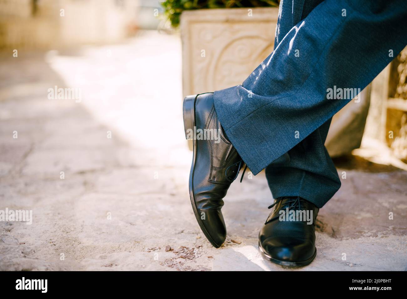 Piedi maschi in scarpe nere e pantaloni blu sul pavimento in pietra. Primo piano Foto Stock