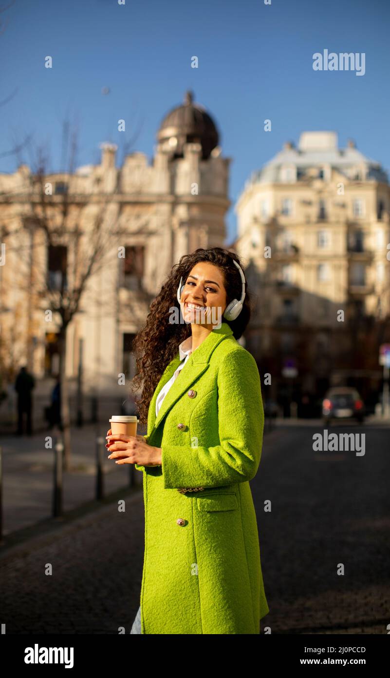 Bella giovane donna che ascolta musica con le cuffie per strada Foto Stock