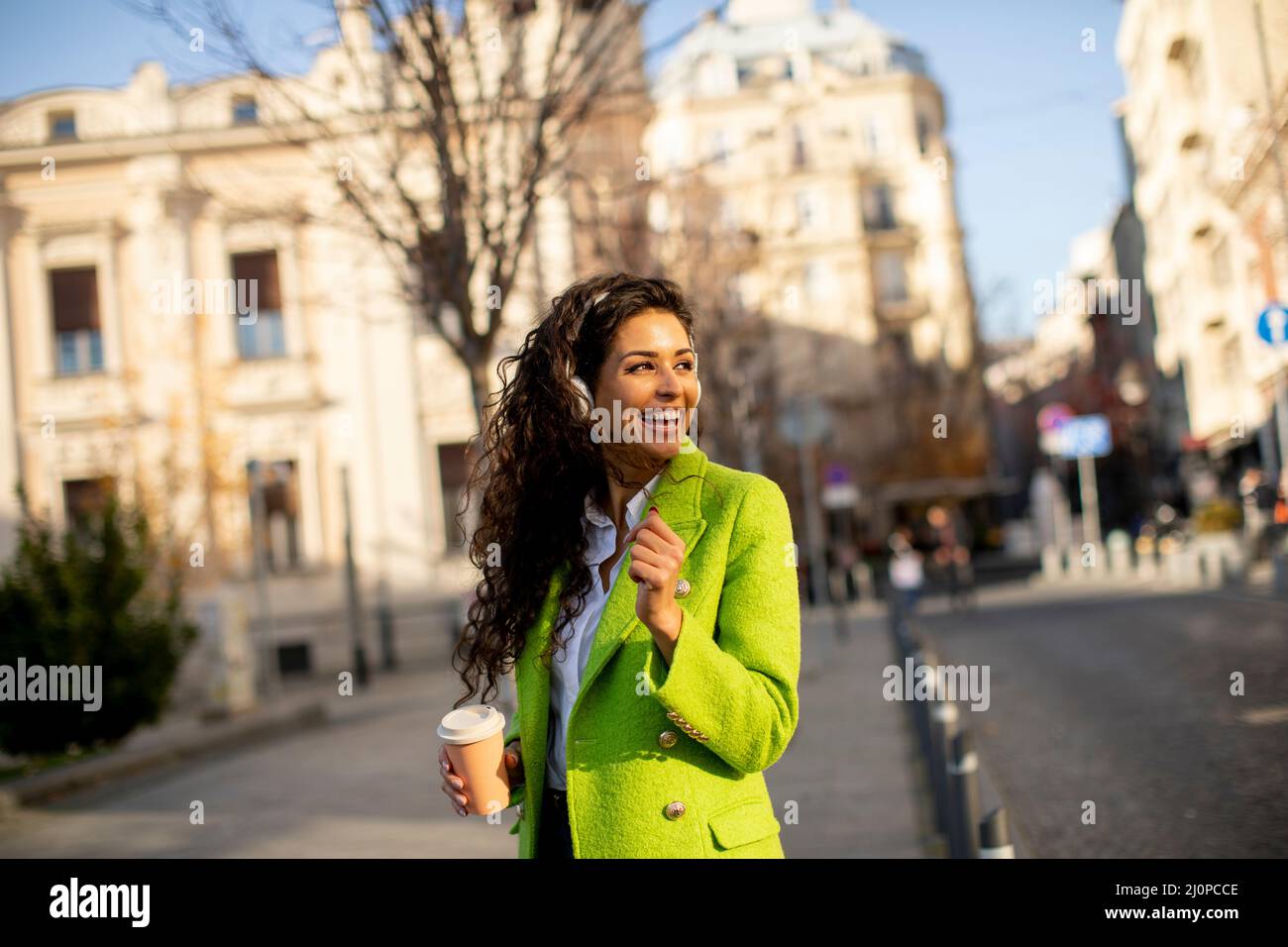 Bella giovane donna che ascolta musica con lo smartphone per strada Foto Stock
