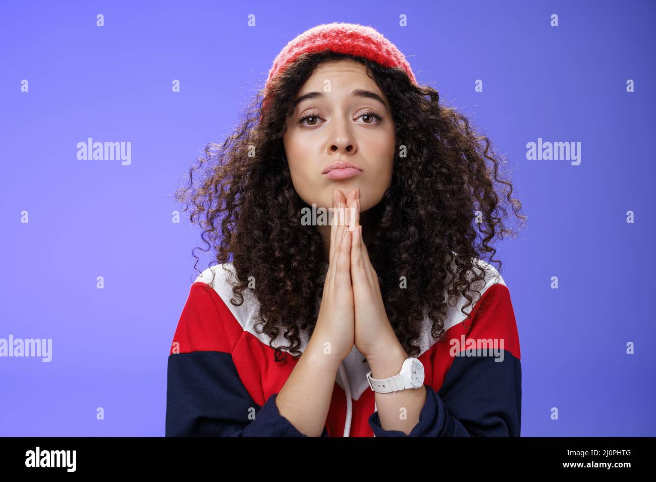 Primo piano di una simpatica ragazza femminile che chiede di portare i suoi dolci preferiti tenendo le mani in pregare le labbra pieghevoli e guardando con un Foto Stock