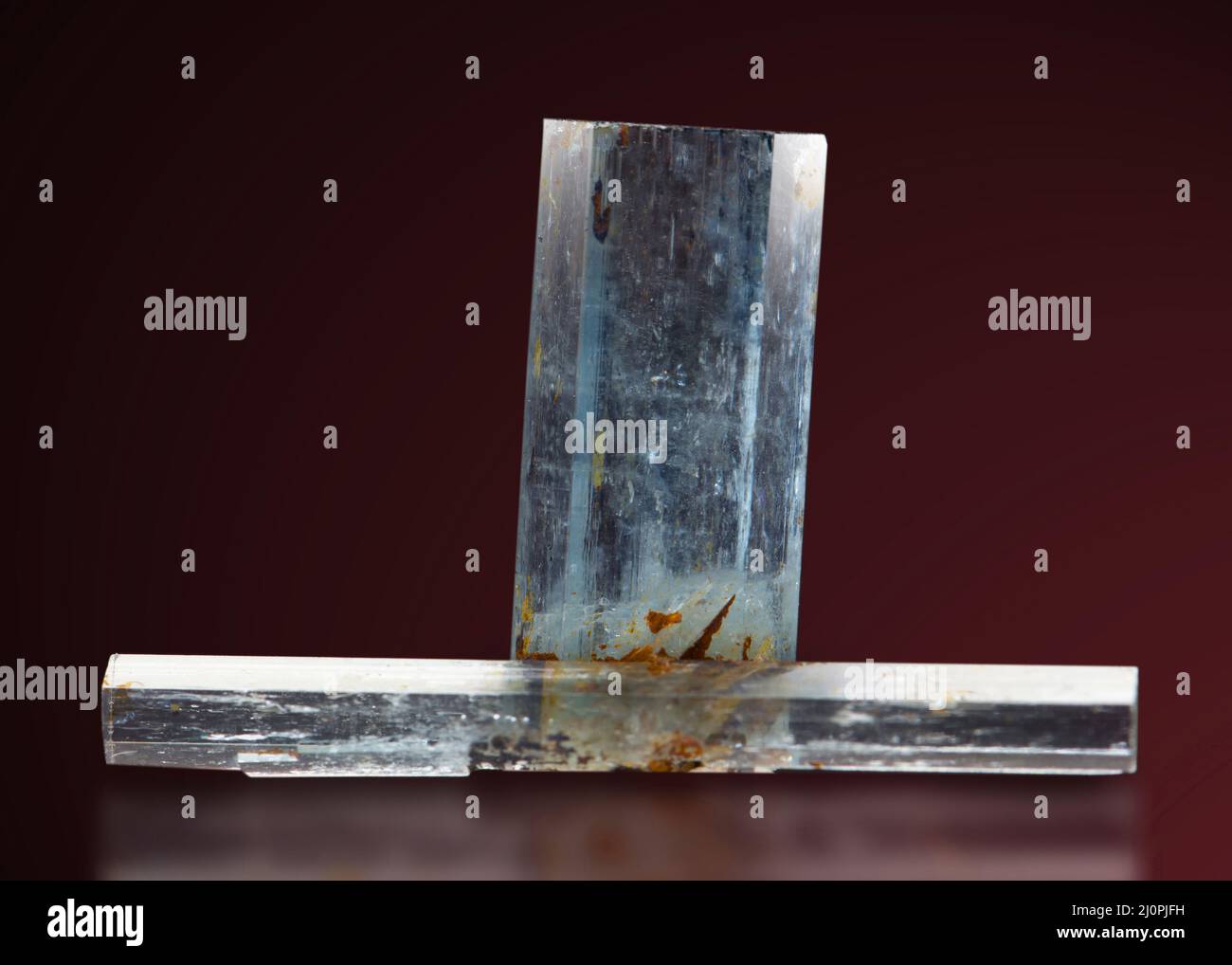 Primo piano di gemma minerale acquamarina isolata su sfondo rosso scuro Foto Stock