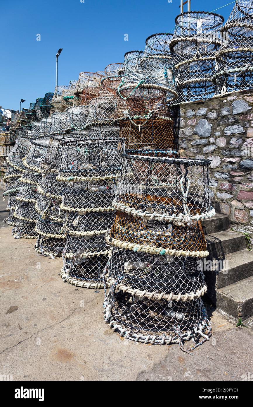 Lobster Pot impilate contro il muro del porto in Brixham Foto Stock