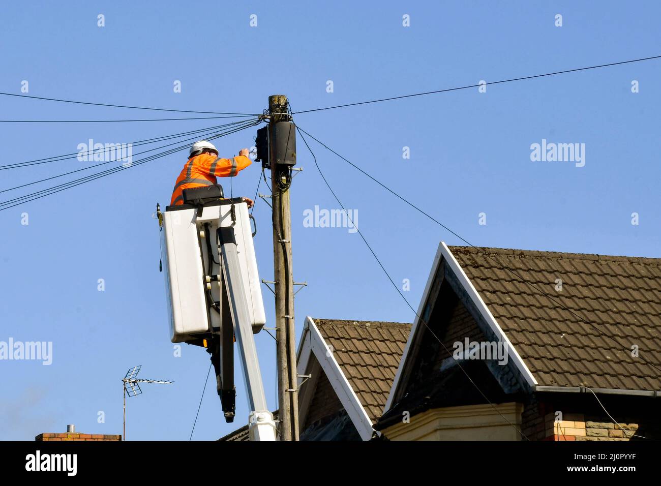 Pontyclun, Galles - marzo 2022: Ingegnere telefonico BT in una piattaforma idraulica cherry picker che ripara i fili su un palo telegrafo. Foto Stock