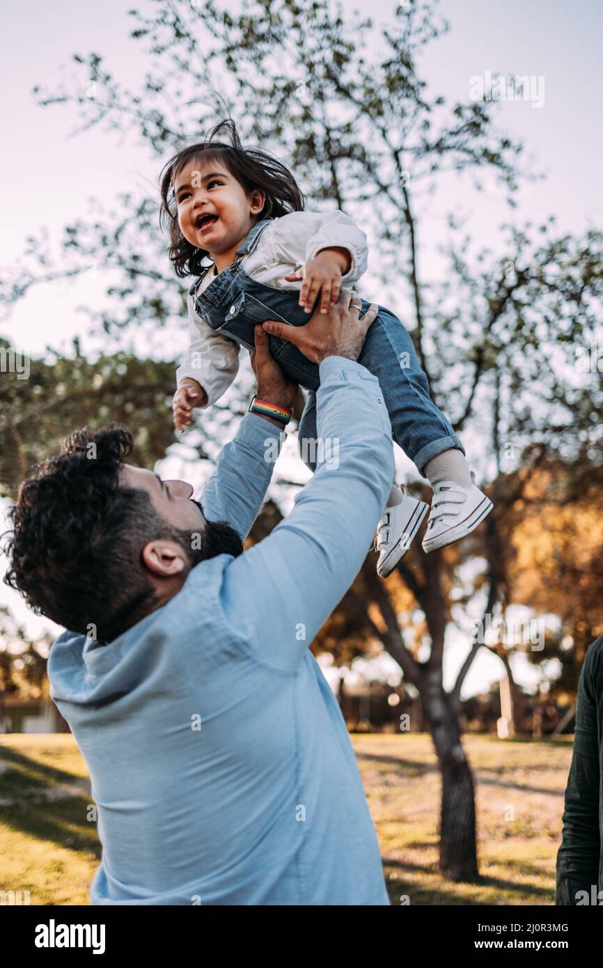 Il padre orgoglioso getta in aria la figlia che ride felicemente. Foto Stock