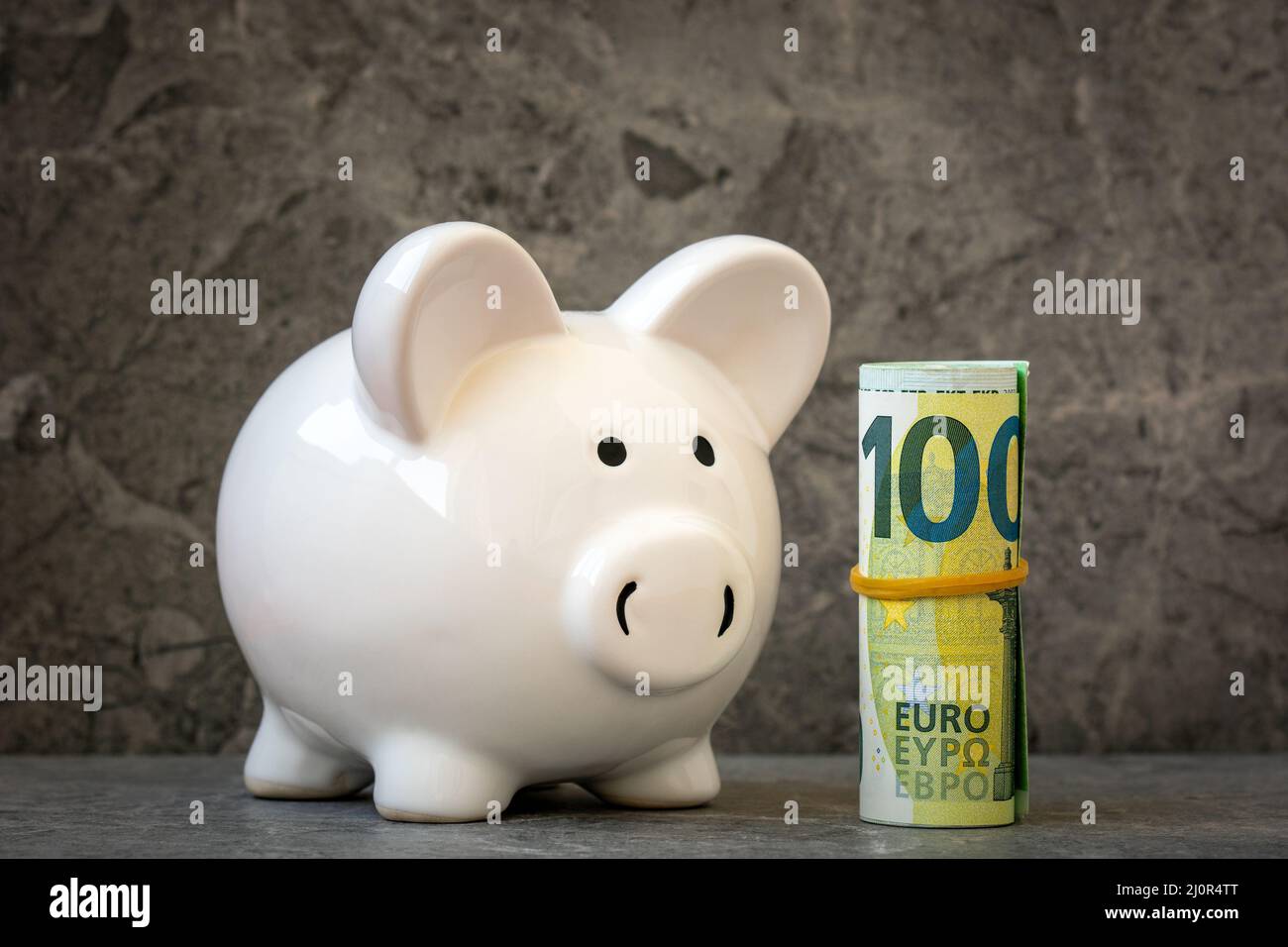 Piggy Bank si trova vicino al rotolo di cento euro Foto Stock