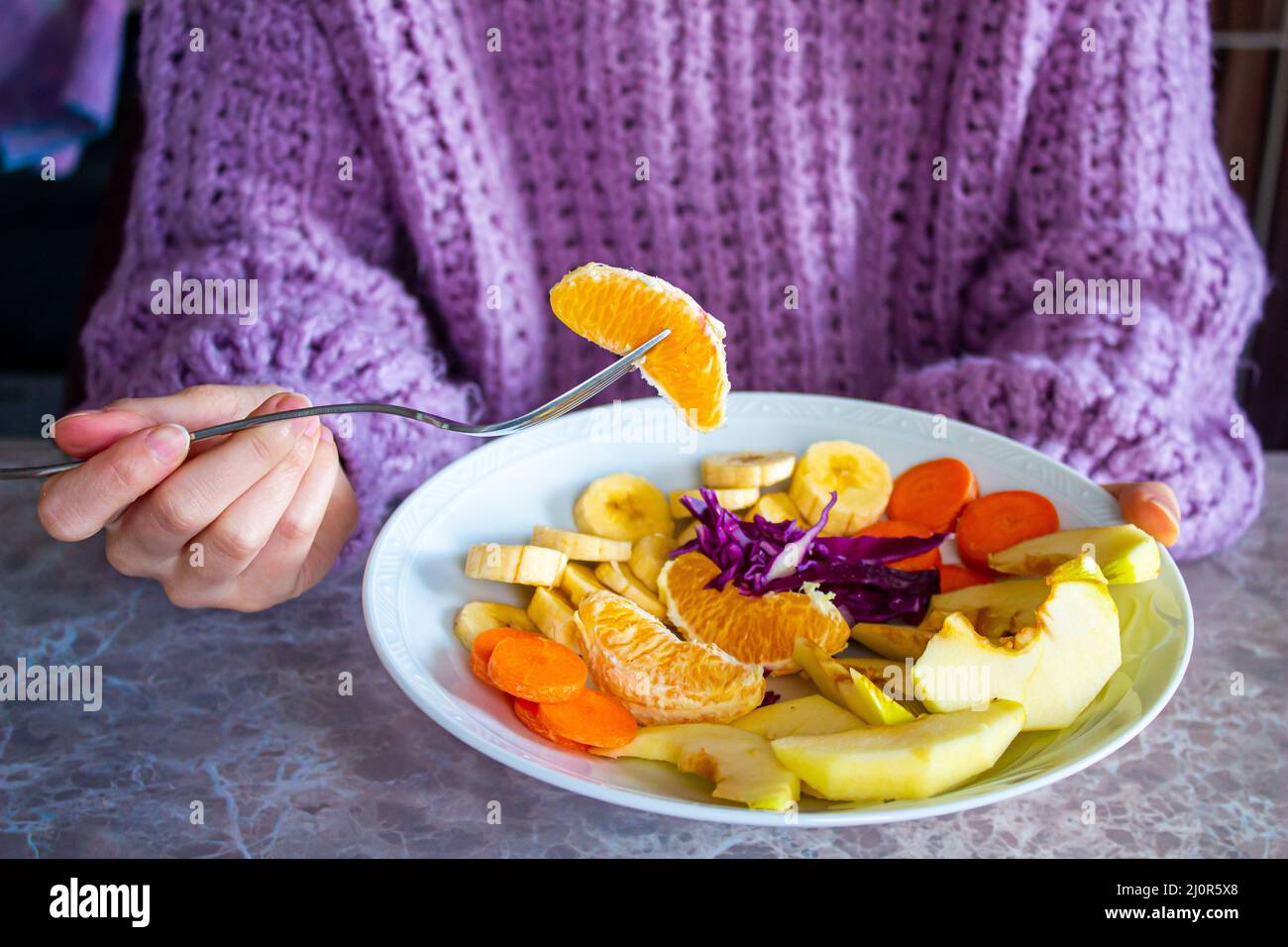 Donna che mangia frutta sana. Primo piano frutta mista in un piatto. Concetto di alimentazione e dieta sana. Foto Stock