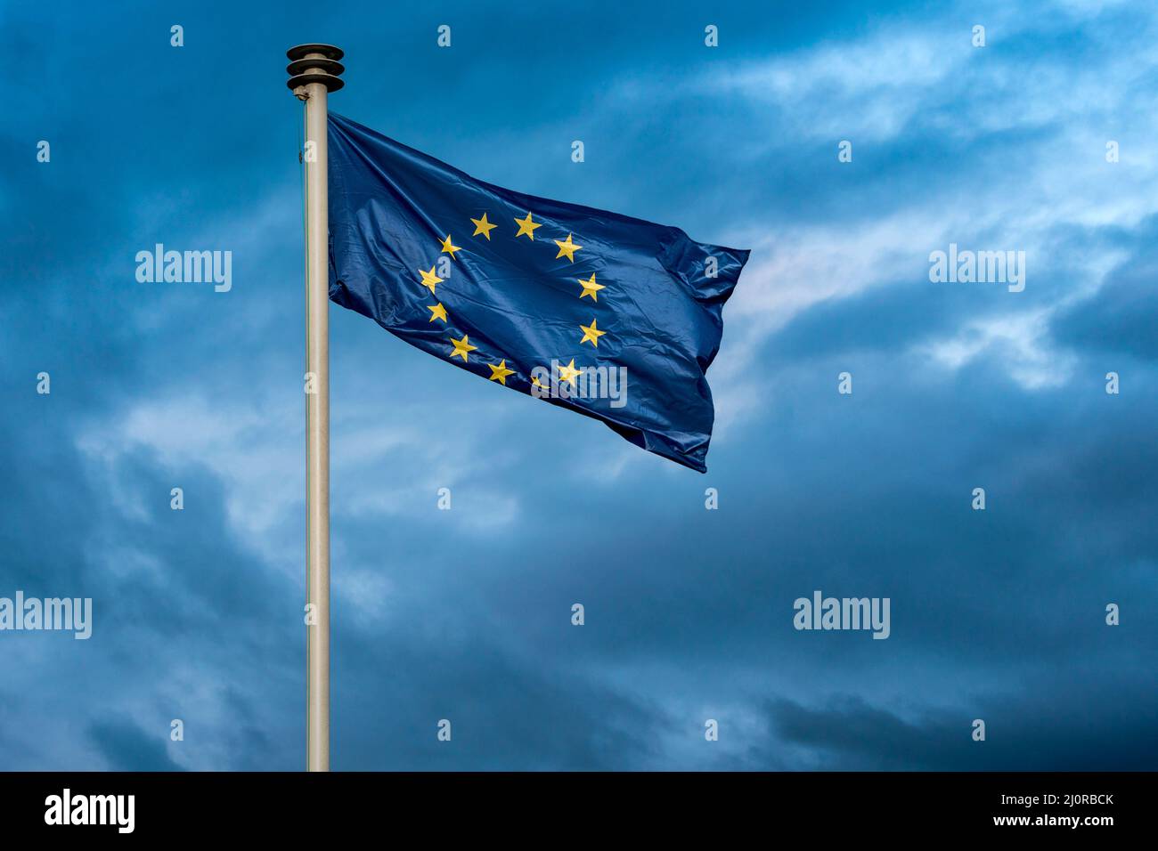 La bandiera dell'Unione europea sventola sullo sfondo di un cielo tempestoso Foto Stock