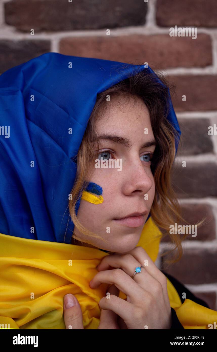 ritratto di una giovane donna avvolta in un panno giallo-blu. Fermare la guerra. Speranza e fede. Rimani con l'Ucraina. La stanchezza e la disperazione della guerra Foto Stock