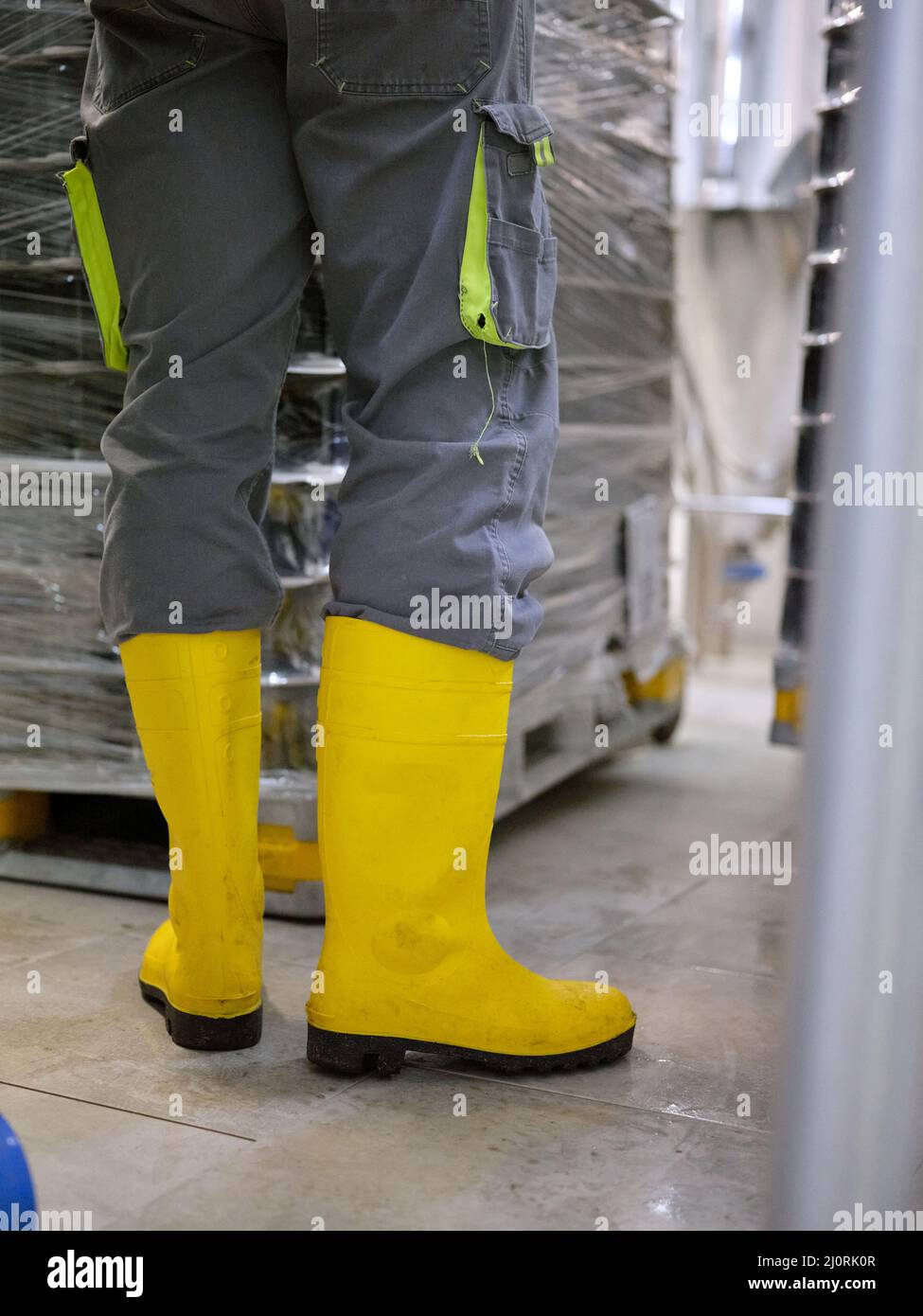 Lavoratore che indossa stivali protettivi in una fabbrica di birra artigianale Foto Stock