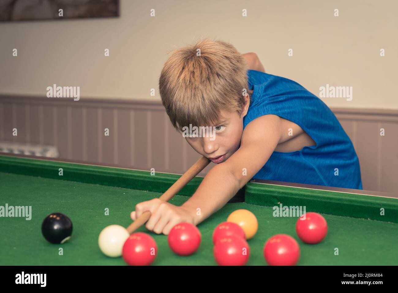 Il ragazzo carino in t shirt blu gioca a biliardo o a biliardo nel club.  Ragazzo con