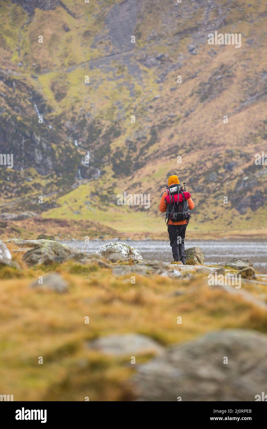 Vai all'aperto: Vista posteriore di escursionista isolato a piedi con zaino in Snowdonia National Park, Galles del Nord, Regno Unito. Foto Stock